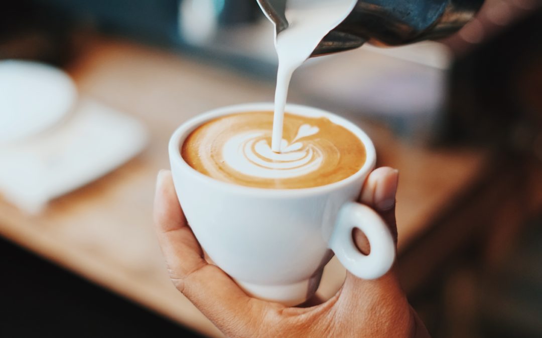Milk being artistically poured into a cup of coffee. Coffee is well known source of caffeine which can impact our energy levels.