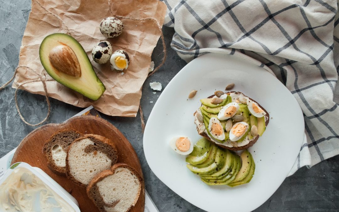 Avocado toast on a white plate, topped with hard boiled eggs. Image from Unsplash.