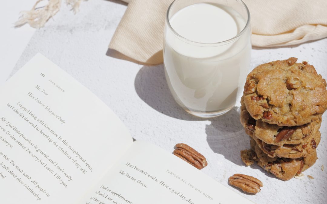 A glass of mix next to a stack of cookies and a book.