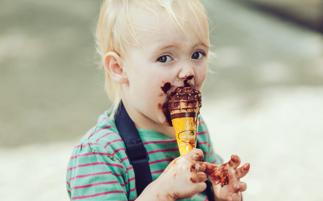 Toddler eating a chocolate ice cream cone.