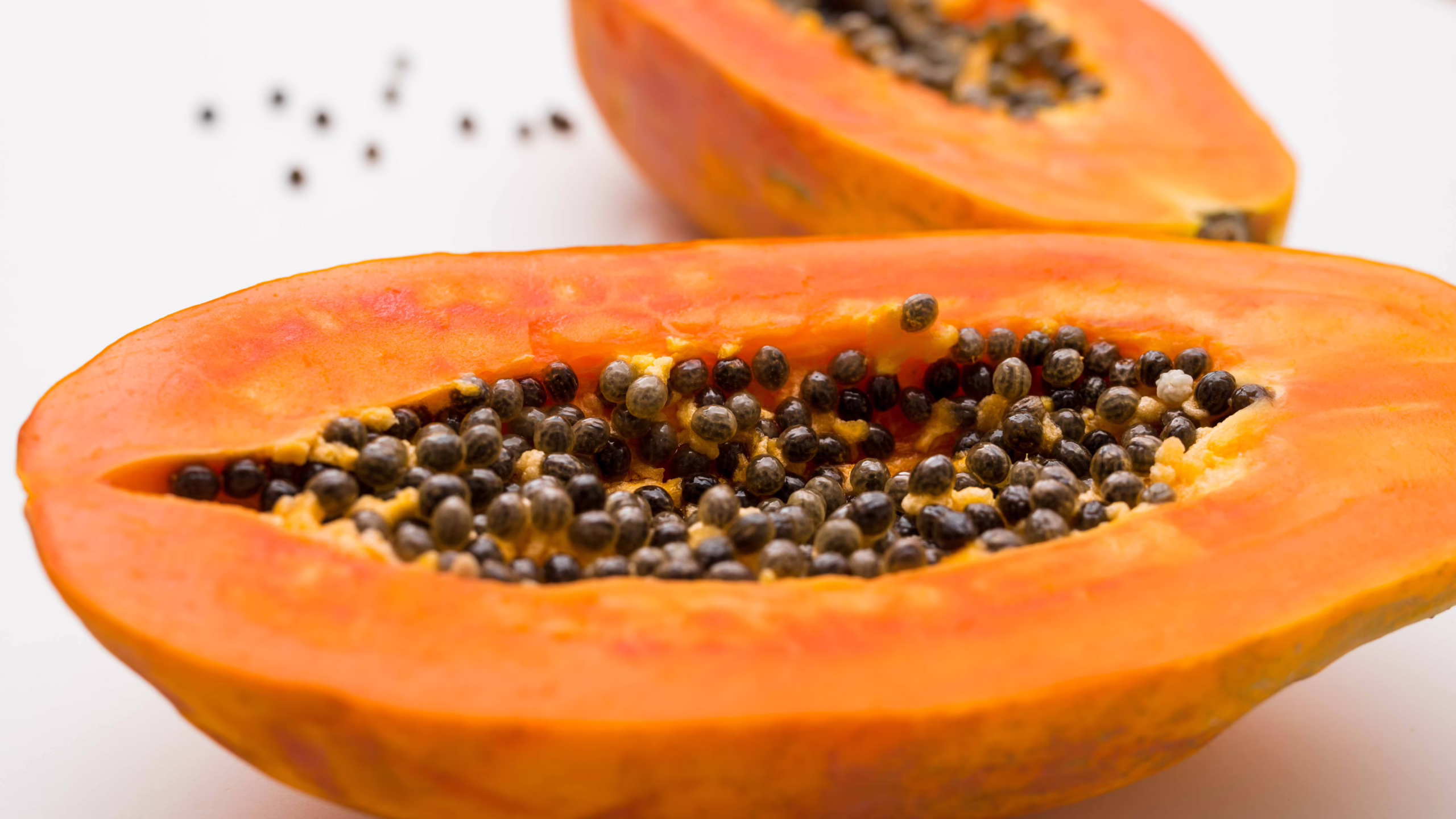 happy-patel-2ZZKGUX2AdQ-unsplash Papaya cut in half on a white background.