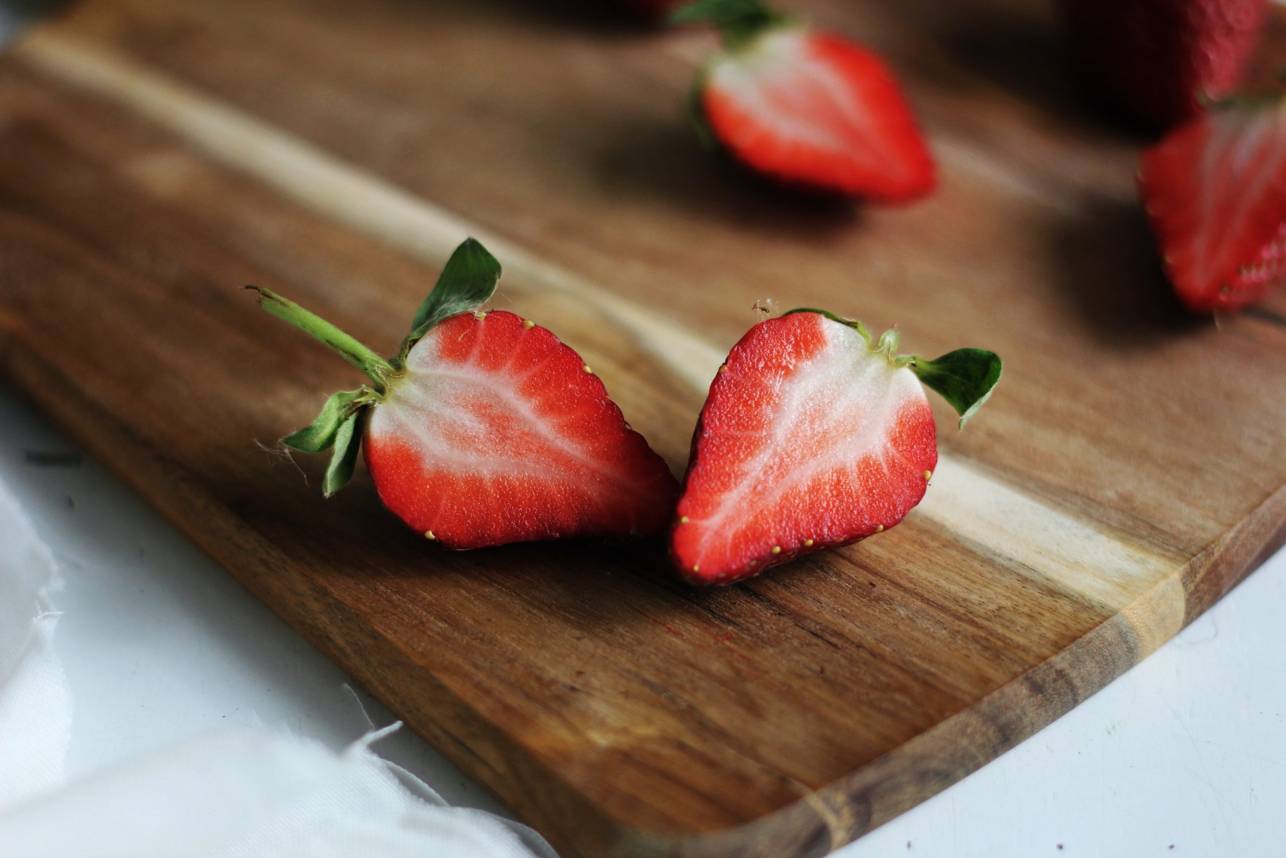 Strawberry sliced in half on a wooden cutting board. Strawberries are an excellent source of vitamin B12 and can reduce our risk of vitamin B12-deficiency anemia.