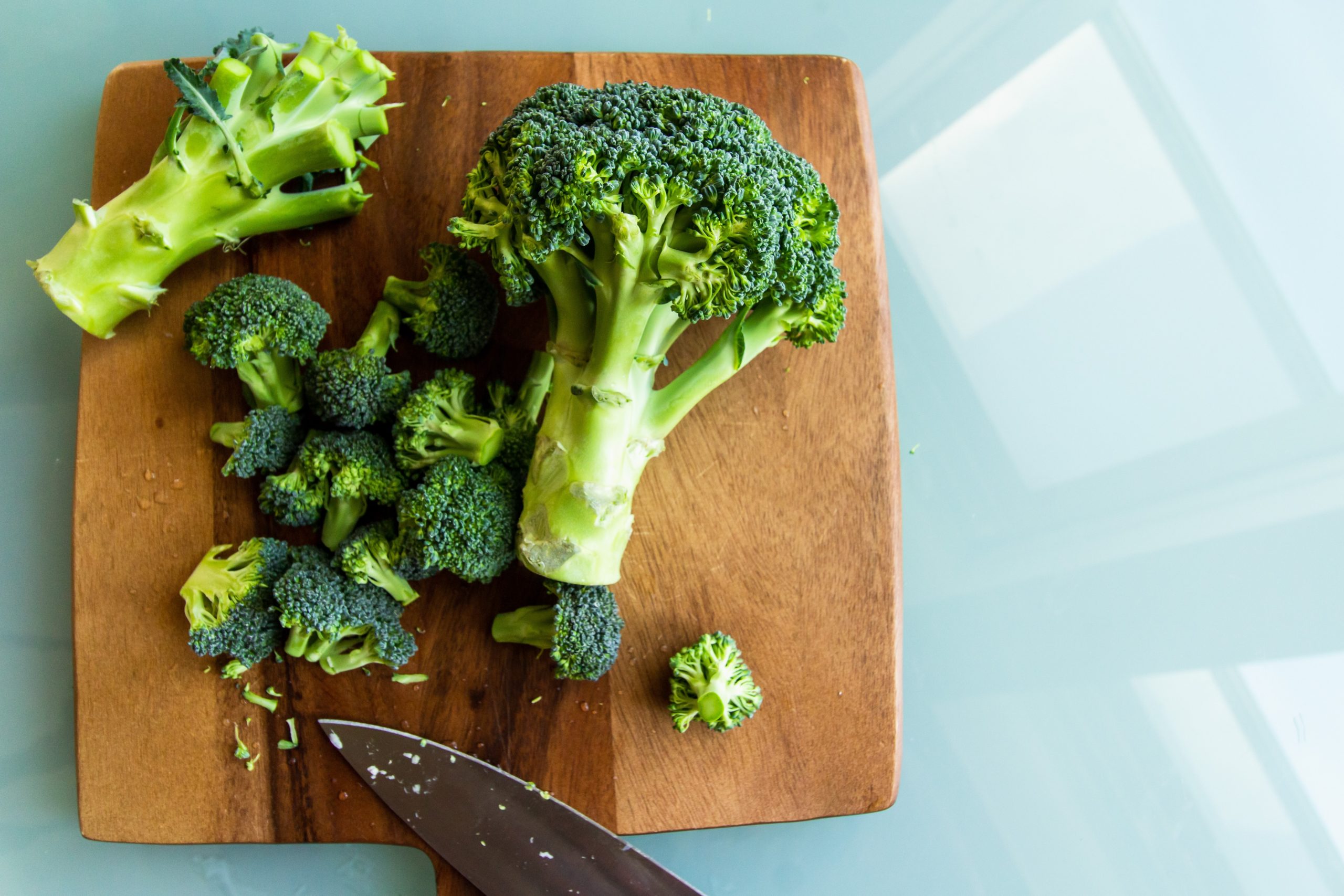 Two heads of broccoli on a chopping board. Broccoli is a good source of folate.