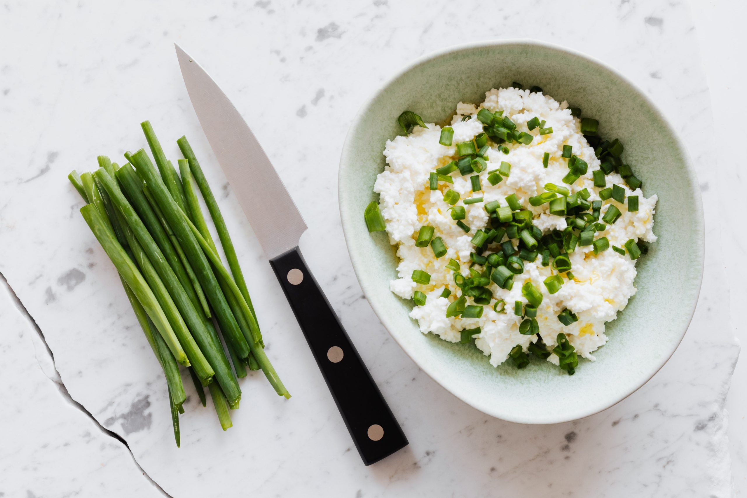 Cottage cheese in a bowl with chives. Cottage cheese contains the mineral selenium.
