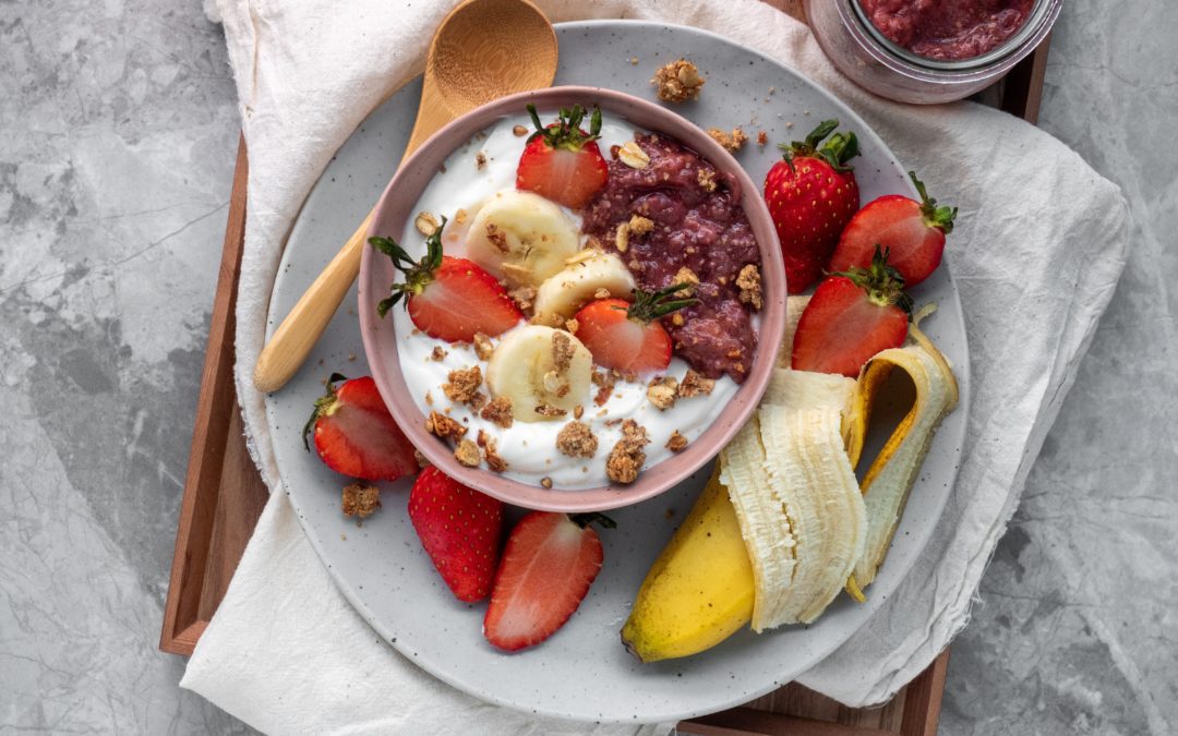 Bowl of yogurt surrounded by sliced strawberries and half a banana. Many foods contain nutrients which support our immune system in protecting our body against pathogens.